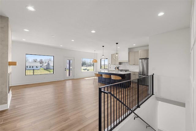 kitchen with light countertops, freestanding refrigerator, a kitchen bar, light wood finished floors, and gray cabinets