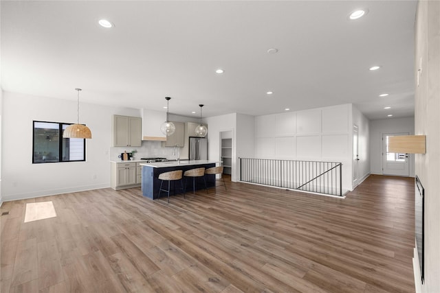 kitchen featuring open floor plan, light countertops, freestanding refrigerator, and light wood finished floors