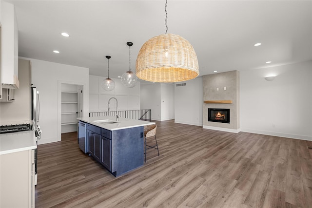 kitchen featuring recessed lighting, light countertops, light wood-style floors, a kitchen bar, and a sink