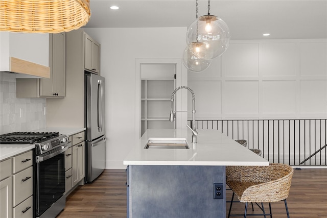 kitchen featuring a decorative wall, dark wood-type flooring, tasteful backsplash, light countertops, and stainless steel appliances