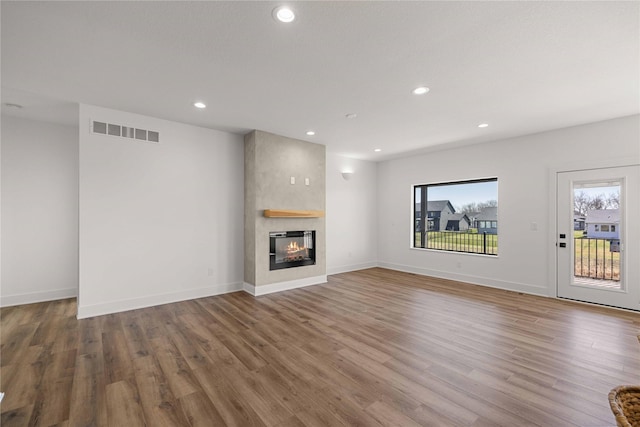 unfurnished living room featuring recessed lighting, visible vents, a large fireplace, and wood finished floors