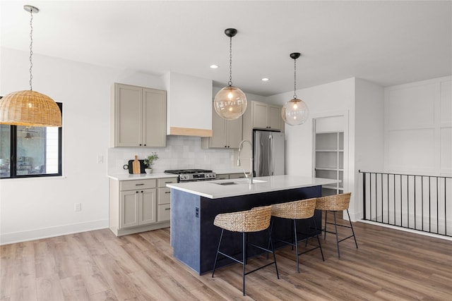 kitchen with a sink, light countertops, freestanding refrigerator, light wood-style floors, and backsplash