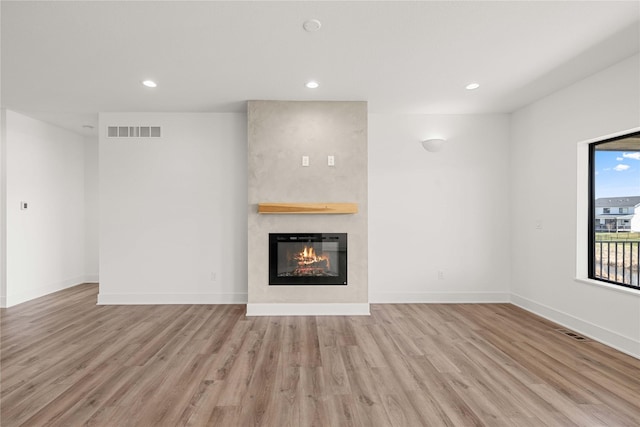 unfurnished living room featuring recessed lighting, a fireplace, visible vents, and wood finished floors