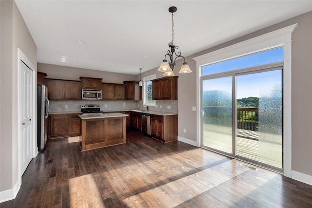 3555 NW 164th St, Clive, IA 50325 - kitchen with appliances with stainless steel finishes, a kitchen island, dark wood-type flooring, decorative backsplash, and light countertops