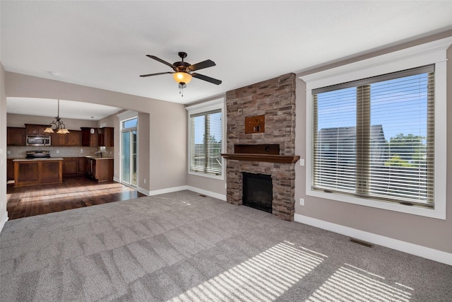 3555 NW 164th St, Clive, IA 50325 - unfurnished living room with carpet floors, a stone fireplace, ceiling fan, and a chandelier