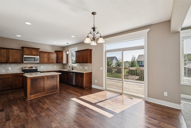 3555 NW 164th St, Clive, IA 50325 - kitchen featuring appliances with stainless steel finishes, dark wood-style flooring, tasteful backsplash, a chandelier, and a center island