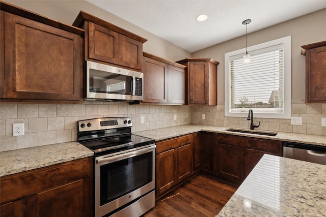 3555 NW 164th St, Clive, IA 50325 - kitchen with appliances with stainless steel finishes, dark wood-type flooring, light stone counters, tasteful backsplash, and pendant lighting