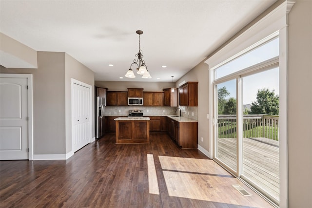 3555 NW 164th St, Clive, IA 50325 - kitchen with appliances with stainless steel finishes, a kitchen island, a chandelier, light countertops, and dark wood-style flooring