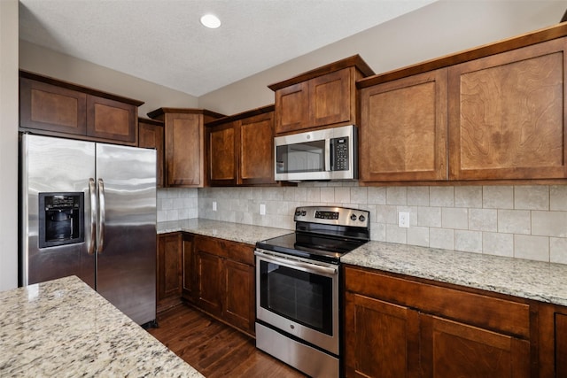 3555 NW 164th St, Clive, IA 50325 - kitchen with stainless steel appliances, dark wood-style flooring, light stone counters, backsplash, and a textured ceiling