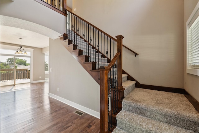 3555 NW 164th St, Clive, IA 50325 - stairway featuring wood finished floors, a chandelier, and arched walkways