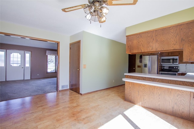 1412 Country Club Dr, Pella, IA 50219 - kitchen featuring appliances with stainless steel finishes, ceiling fan, a peninsula, light countertops, and light wood-style flooring