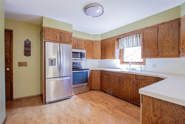 1412 Country Club Dr, Pella, IA 50219 - kitchen featuring appliances with stainless steel finishes, a sink, brown cabinetry, and tasteful backsplash