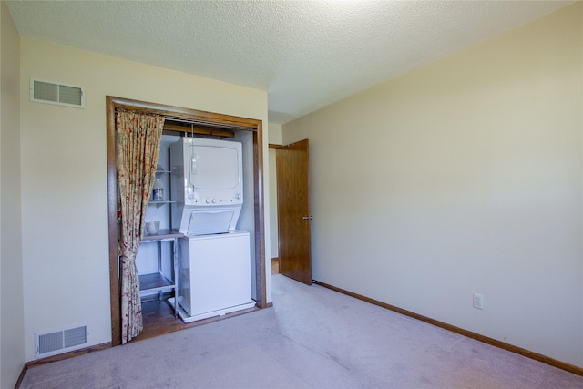 1412 Country Club Dr, Pella, IA 50219 - carpeted spare room featuring stacked washer / dryer, baseboards, and a textured ceiling