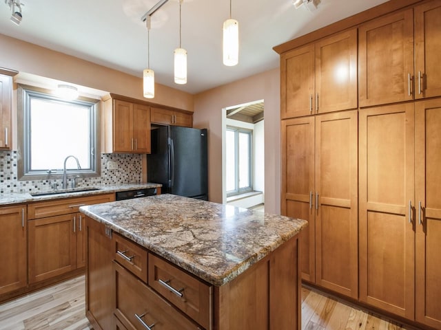 kitchen with light wood finished floors, a sink, brown cabinetry, a kitchen island, and black appliances