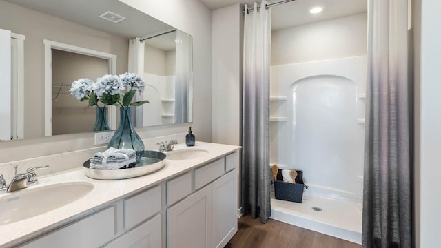 bathroom with a sink, visible vents, a stall shower, and wood finished floors