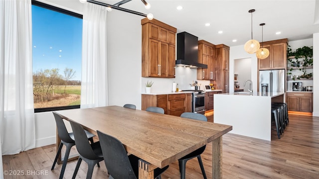 18170 79th Ln, Indianola, IA 50125 - kitchen with brown cabinets, appliances with stainless steel finishes, and wall chimney range hood