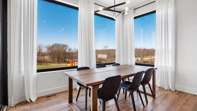 18170 79th Ln, Indianola, IA 50125 - dining room featuring light wood-style floors, an inviting chandelier, baseboards, and visible vents