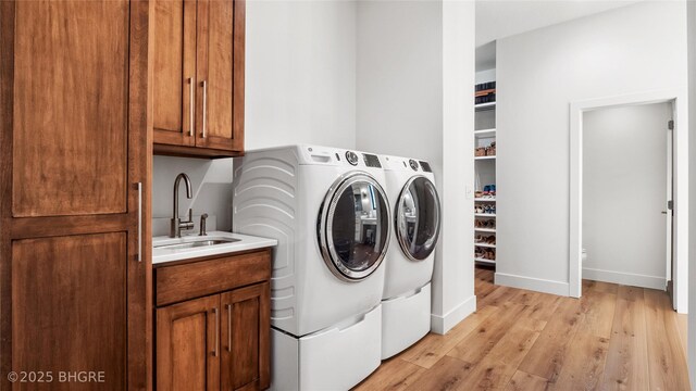 18170 79th Ln, Indianola, IA 50125 - laundry area with baseboards, a sink, light wood-style floors, independent washer and dryer, and cabinet space