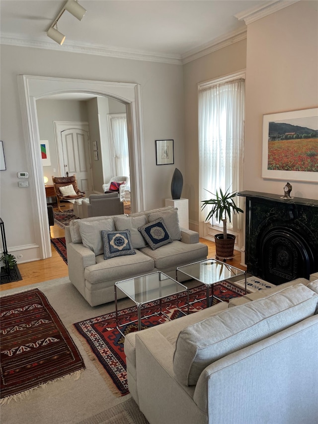 living room with crown molding, arched walkways, and a fireplace with flush hearth