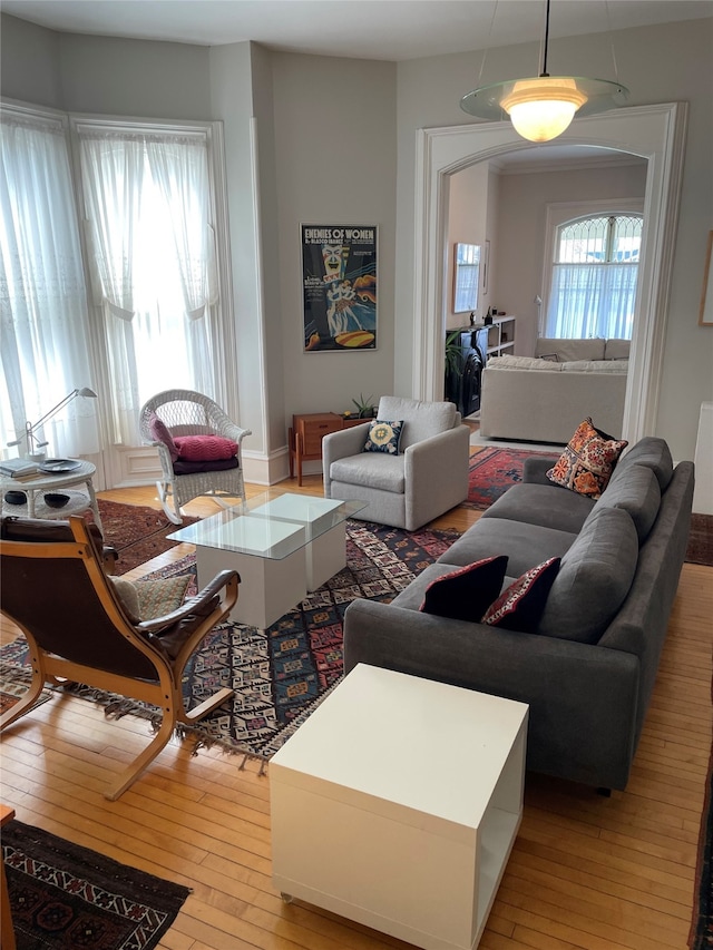 living area with light wood-style floors and arched walkways