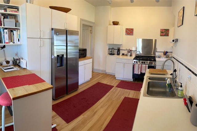 kitchen featuring wood counters, appliances with stainless steel finishes, a sink, and light wood-type flooring