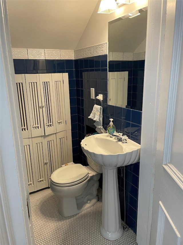 bathroom featuring tile walls, toilet, vaulted ceiling, and tile patterned flooring