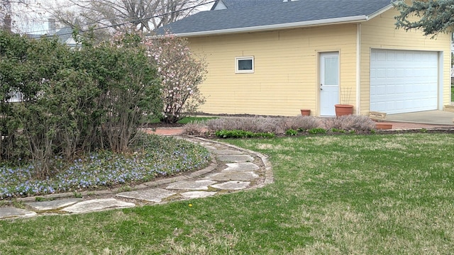 view of side of home with roof with shingles and a yard