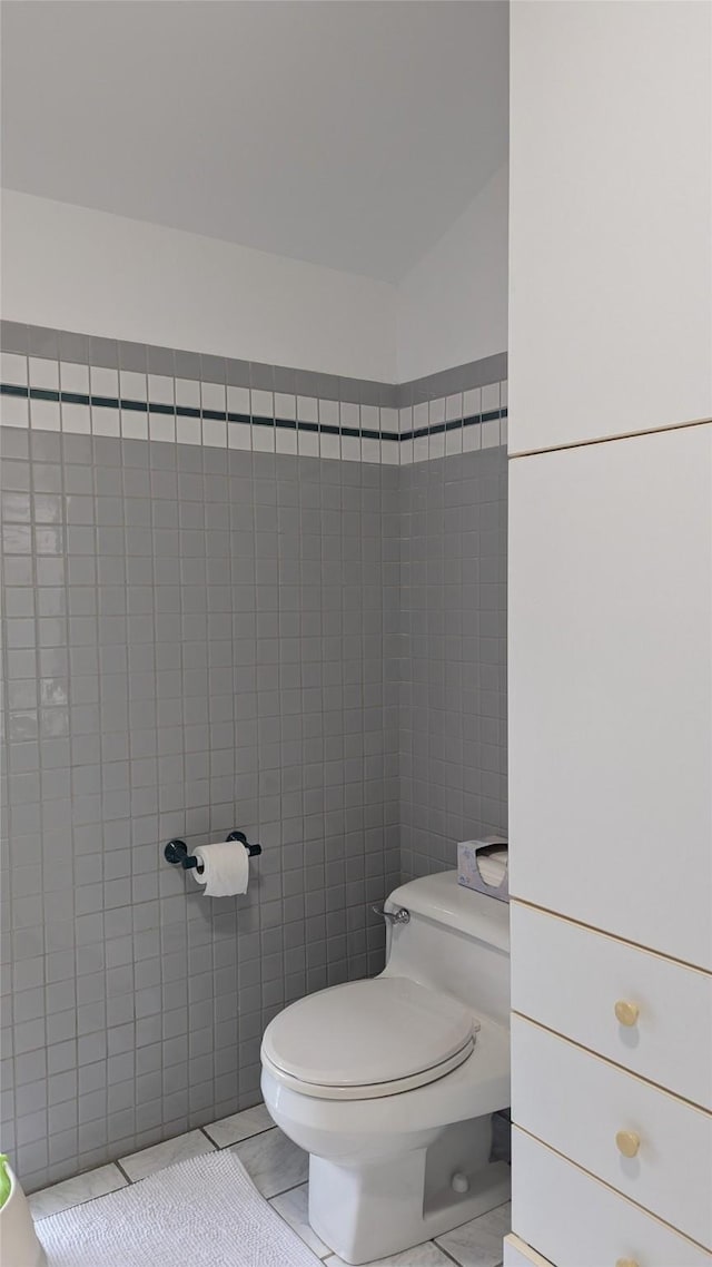 bathroom with toilet and tile walls