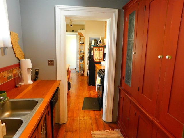 corridor with light wood-style floors and a sink