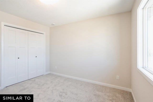 unfurnished bedroom with a closet, carpet flooring, and baseboards
