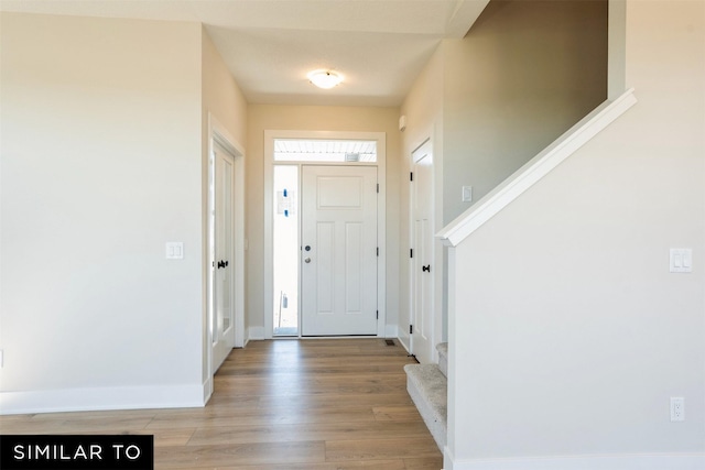 entrance foyer with baseboards, light wood-type flooring, and stairs
