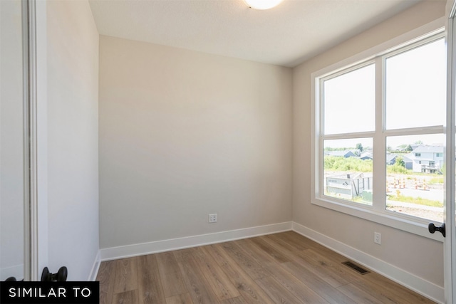 unfurnished room featuring light wood-style flooring, visible vents, and baseboards
