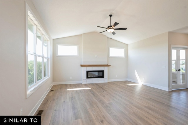 unfurnished living room with light wood-style floors, a tile fireplace, ceiling fan, and plenty of natural light