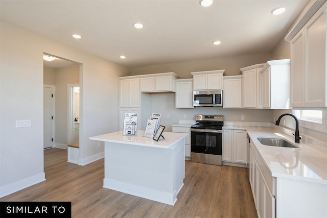 kitchen featuring white cabinets, a sink, light wood-type flooring, appliances with stainless steel finishes, and recessed lighting