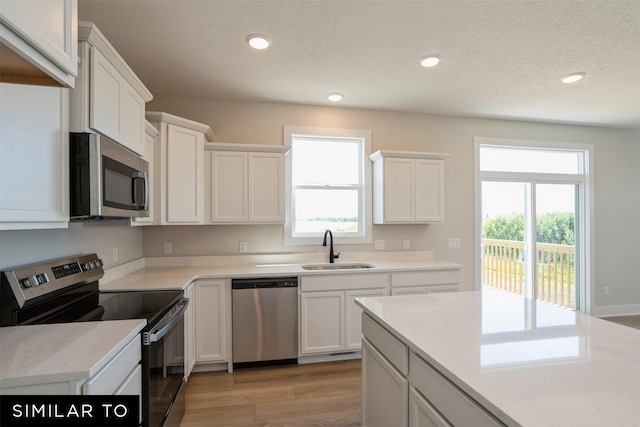 kitchen featuring a sink, a wealth of natural light, appliances with stainless steel finishes, and white cabinetry