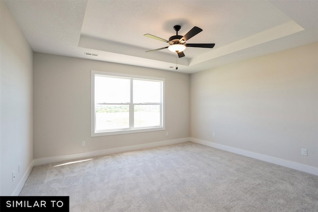 unfurnished room with visible vents, baseboards, a raised ceiling, and light carpet