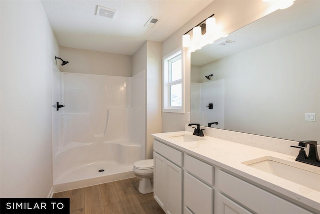 bathroom featuring a shower, wood finished floors, a sink, and visible vents