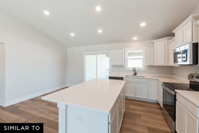 kitchen with a sink, light wood-type flooring, white cabinetry, stainless steel appliances, and a kitchen island