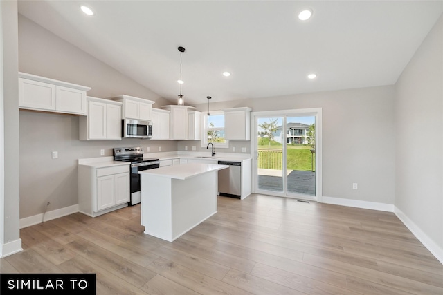 kitchen with stainless steel appliances, white cabinets, a center island, and a sink