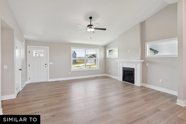 unfurnished living room featuring a fireplace, light wood-style flooring, a ceiling fan, lofted ceiling, and baseboards