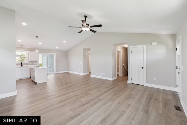 unfurnished living room featuring light wood-type flooring, ceiling fan, a sink, and visible vents
