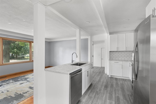 1150 SW Lynn Dr, Ankeny, IA 50023 - kitchen featuring appliances with stainless steel finishes, light stone counters, light wood-type flooring, white cabinetry, and tasteful backsplash