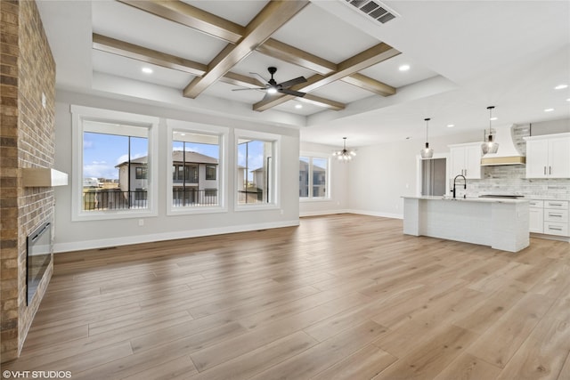 unfurnished living room with visible vents, baseboards, a sink, a fireplace, and coffered ceiling
