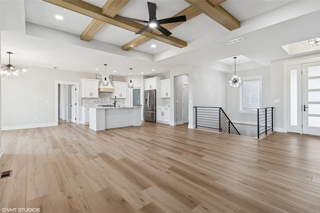 unfurnished living room featuring visible vents, baseboards, beamed ceiling, light wood finished floors, and coffered ceiling