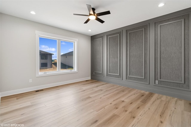 spare room with light wood-style floors, ceiling fan, baseboards, and visible vents