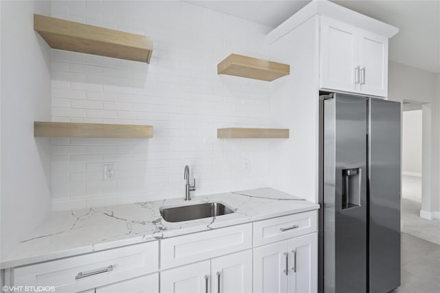kitchen featuring stainless steel fridge with ice dispenser, white cabinetry, backsplash, open shelves, and a sink