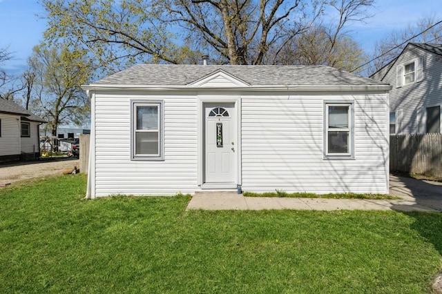 view of front of property with a front yard, fence, and a shingled roof