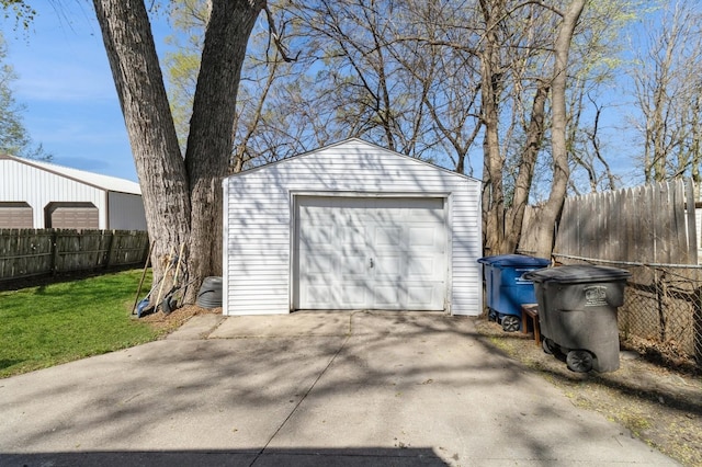 detached garage with concrete driveway and fence