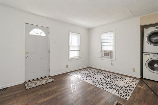 entrance foyer with a textured ceiling, wood finished floors, baseboards, and stacked washer / drying machine