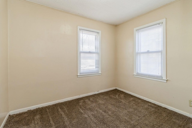 spare room with dark carpet, baseboards, and ornamental molding